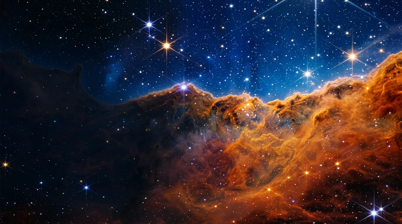 Towering orange gas pillars of the Carina Nebula against a blue starfield
