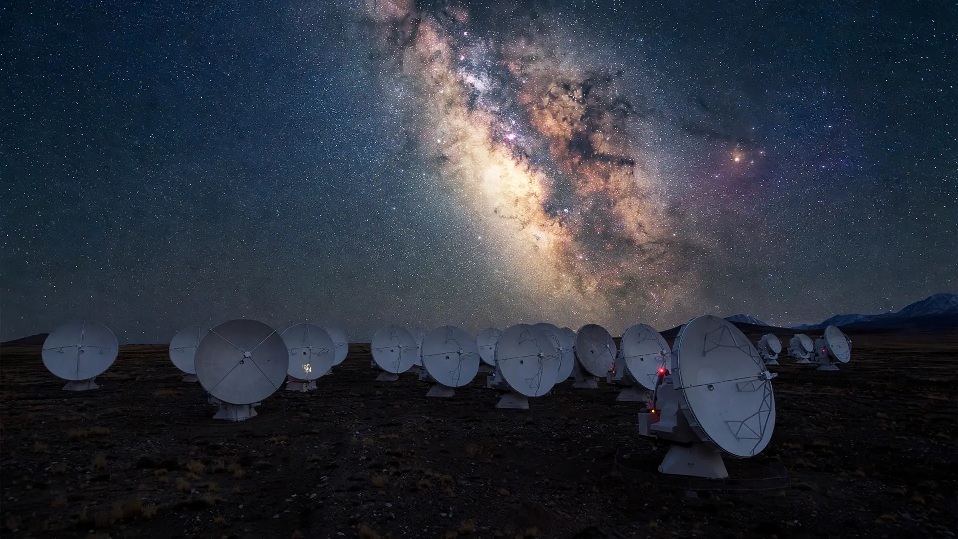 Radio dishes of the Event Horizon Telescope array under the Milky Way, the galactic center glowing above